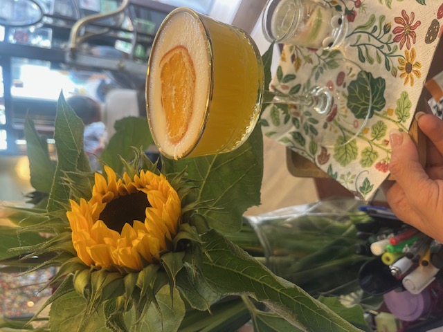 Een fris aperitief met gedroogde sinaasappel, naast een boeket zonnebloemen